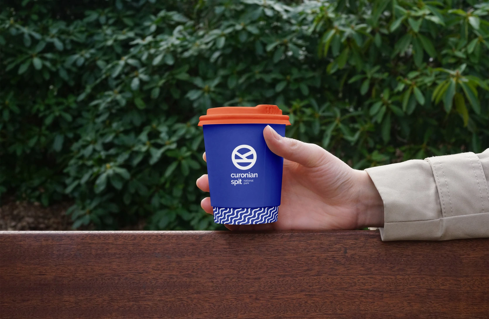 Branded cup held against a green background